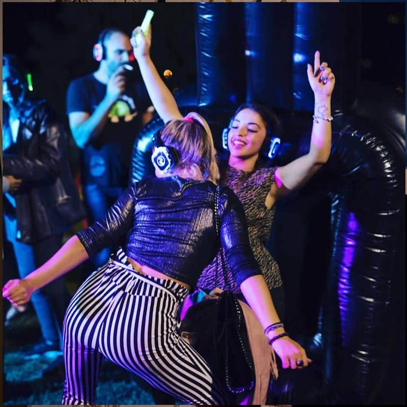 Amigos bailando con cascos de silent party iluminados
