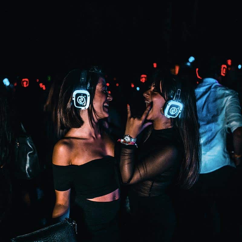 Vecinos bailando con cascos de silent party en una fiesta de verano