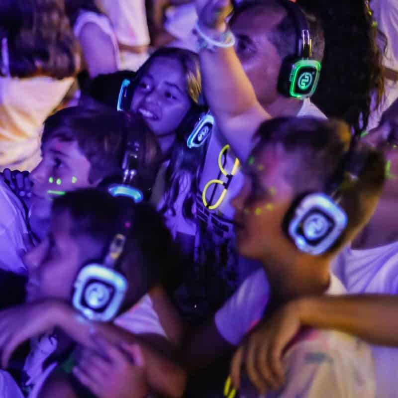 Grupo de niños con cascos inalámbricos iluminados en una fiesta