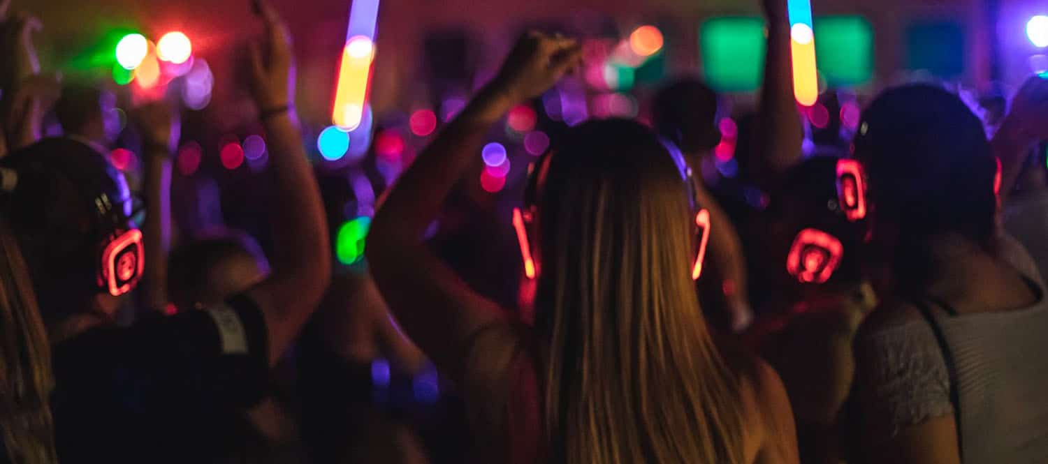 Chicas bailando con cascos de silent party iluminados de colores